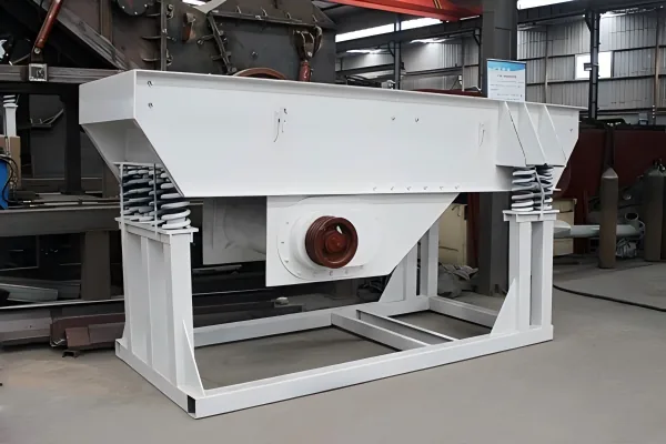 Vibrating feeder for controlled ore delivery to a grinding circuit